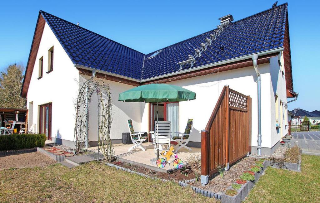 una casa con patio con ombrellone e sedie verdi di Cozy Apartment In Wesenberg With Kitchen a Wesenberg