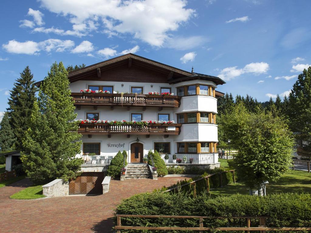 ein großes weißes Gebäude mit Balkonen und Bäumen in der Unterkunft KREUZHOF Seefeld in Seefeld in Tirol