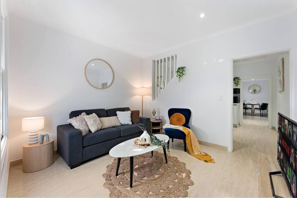 uma sala de estar com um sofá azul e uma mesa em Beautiful 3BR House Close to Central Station em Sydney