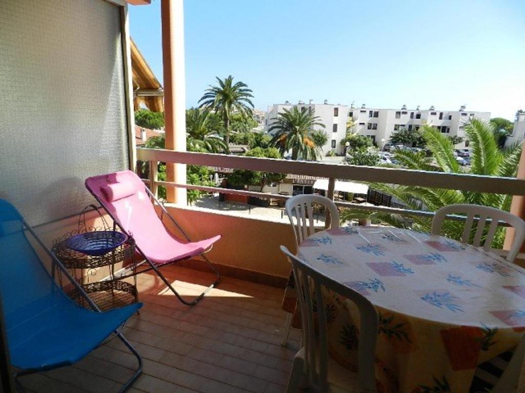 d'un balcon avec une table et des chaises et une vue sur un bâtiment. dans l'établissement Appartement cocooning 4 pers, accès plage et commerces, parking privé, ménage inclus - FR-1-251-665, à Bormes-les-Mimosas