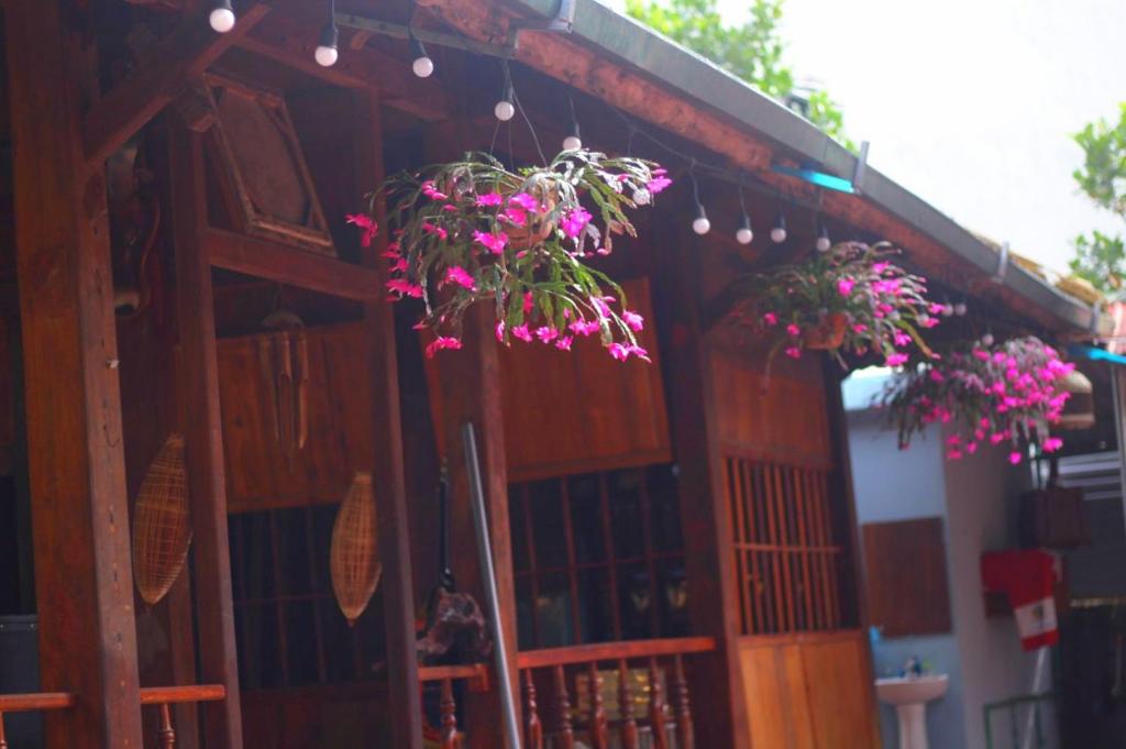 un bâtiment avec des fleurs roses suspendues dans l'établissement Pu Home Đỗ Quyên (Homestay Đỗ Quyên), à Bản Hon