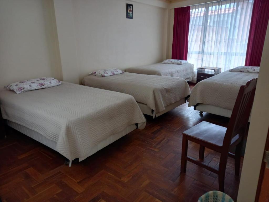 een kamer met 3 bedden en een stoel bij Hostal Venegas in Copacabana