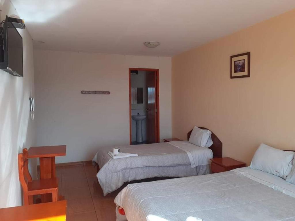 een hotelkamer met 2 bedden en een televisie bij Hostal Vanguts in Huancayo
