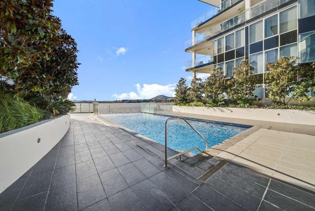 a swimming pool in front of a building at Canberra Lakefront 2-Bed with Pool, Gym & Parking in Kingston 