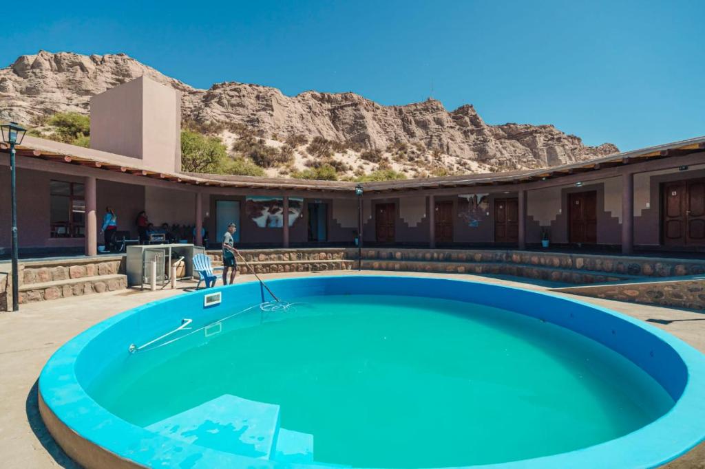 a swimming pool in front of a building with a mountain at Hosteria Puerta de Corral Quemado in Las Juntas