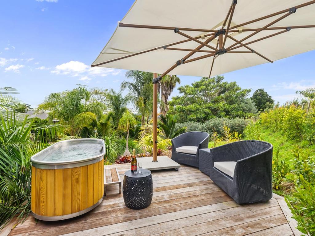 een parasol en stoelen op een terras met een hot tub bij Country Idyll - Sandspit Holiday Cottage in Sandspit