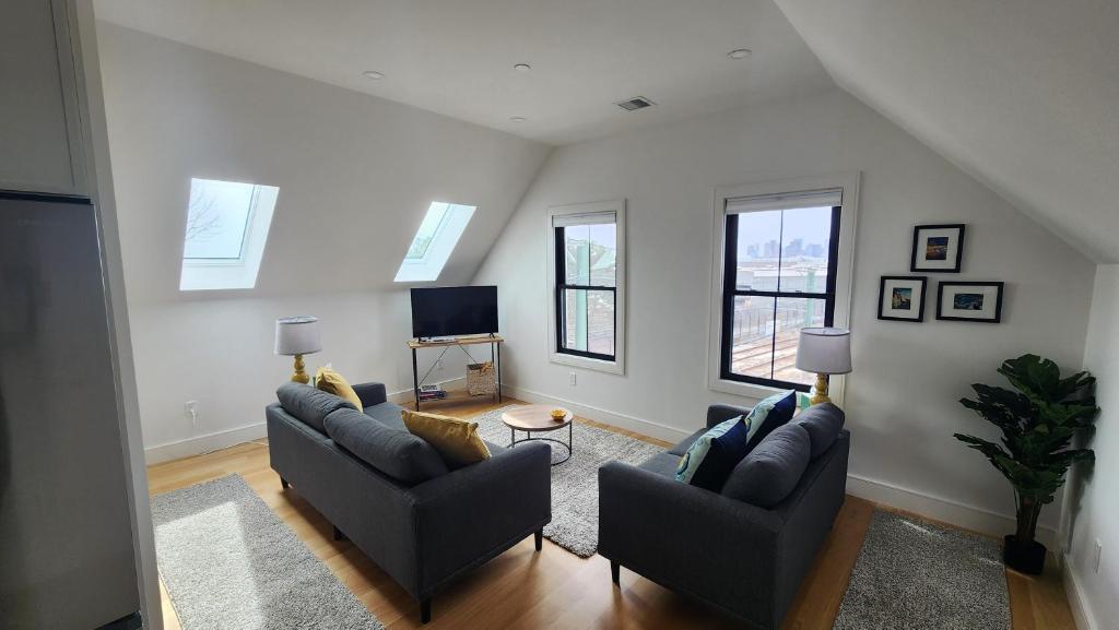 a living room with two couches and a tv at Ultra Convenient East Boston Luxury Condo in Boston