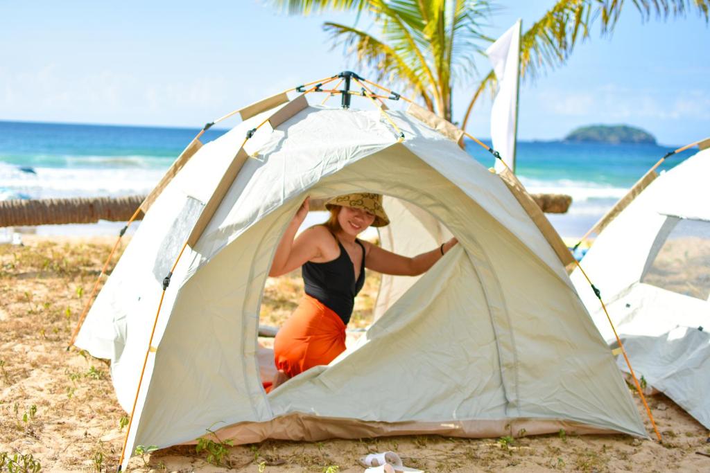 a woman standing inside of a tent on the beach at EL NIDO WATERSPORTS AND ADVENTURES BEACH CAMP in Duli