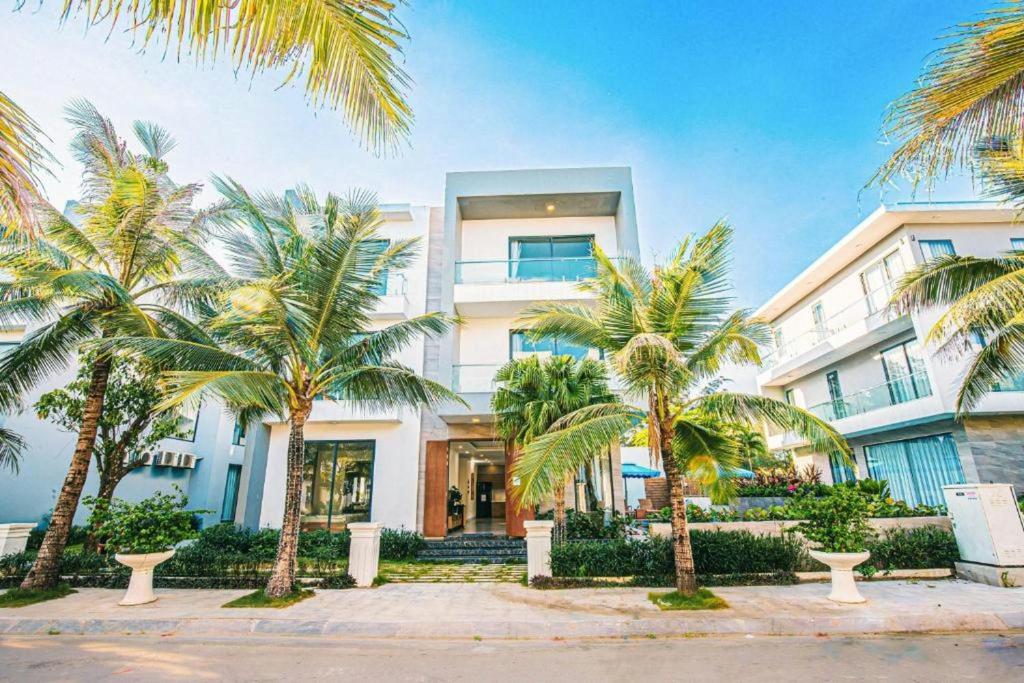 a building with palm trees in front of it at Villa FLC Sầm Sơn Ngọc Trai - Ngay Gần Biển in Sầm Sơn