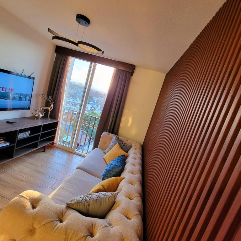 a large couch in a living room with a large window at Elegante apartamento cerca de Embajada de los EEUU y Cayala in Guatemala