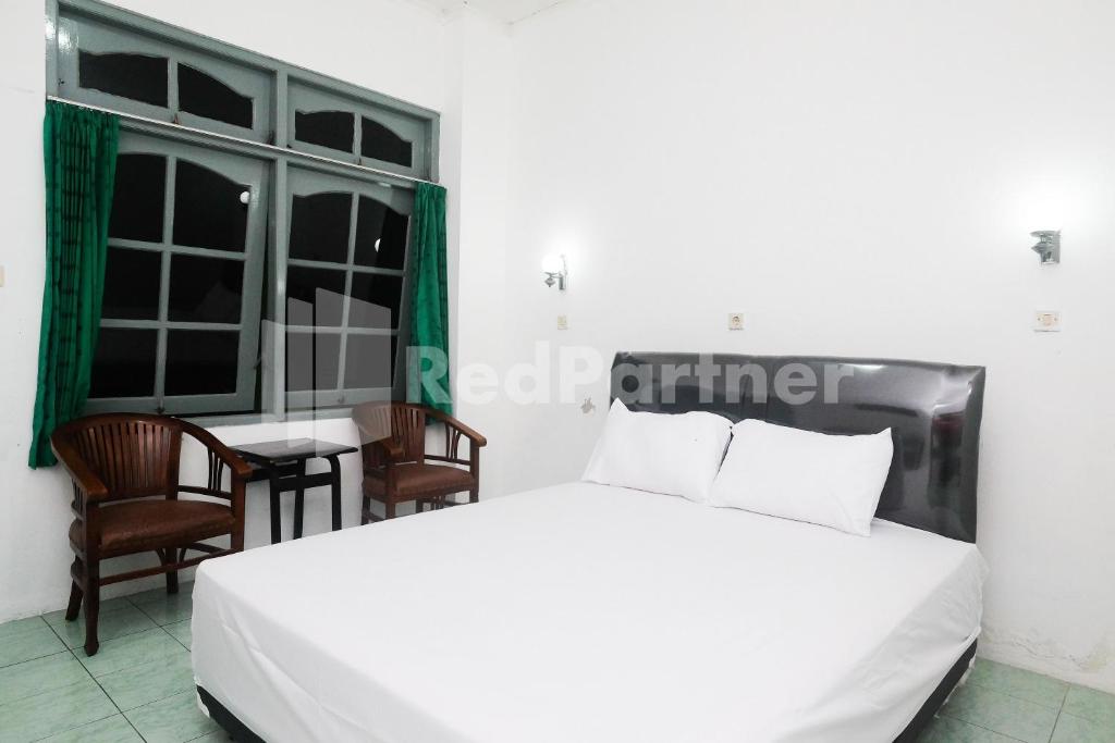a bedroom with a white bed and a table and chairs at Camila Living Yogyakarta RedPartner in Timuran