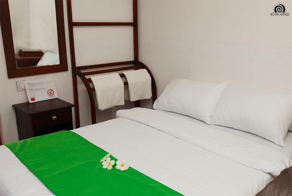Un dormitorio con una cama con una manta verde. en Pearl Lodge, en Polonnaruwa
