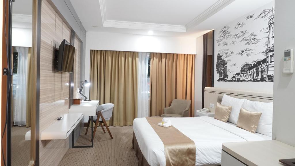 una camera d'albergo con letto e scrivania di Abadi Hotel Malioboro Yogyakarta by Tritama Hospitality a Yogyakarta