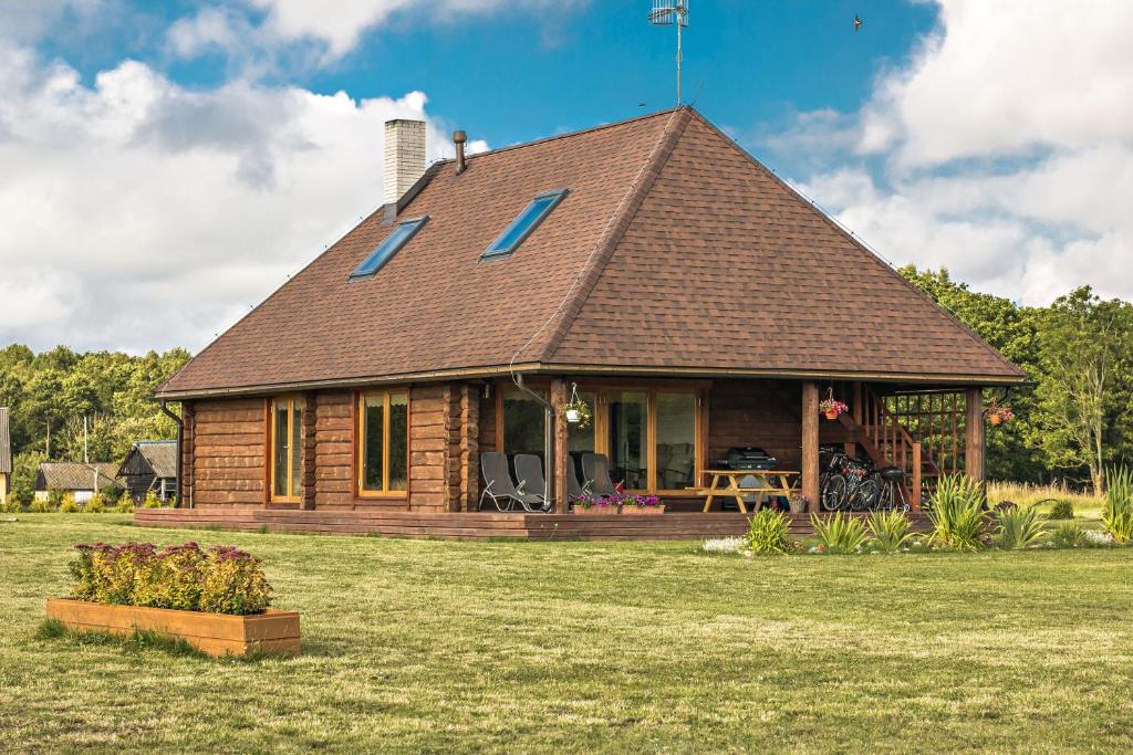 uma cabana de madeira com um alpendre num campo de relva em Rootsimaa Holiday House em Torgu