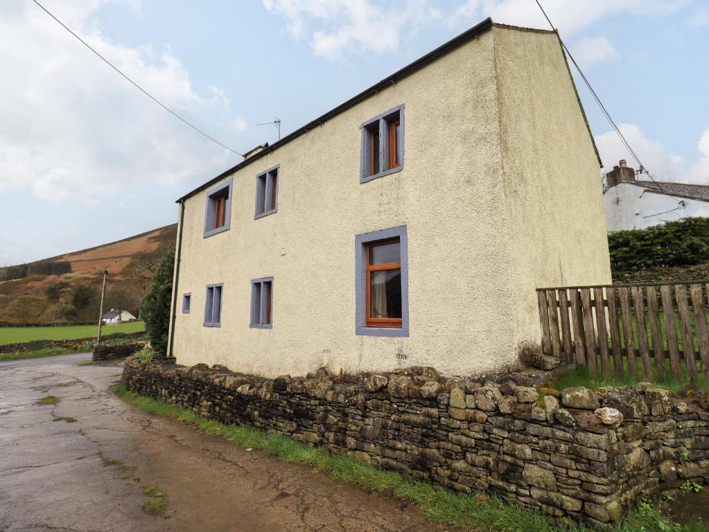 een oud stenen huis aan een stenen muur bij Scales Cottage in Lorton