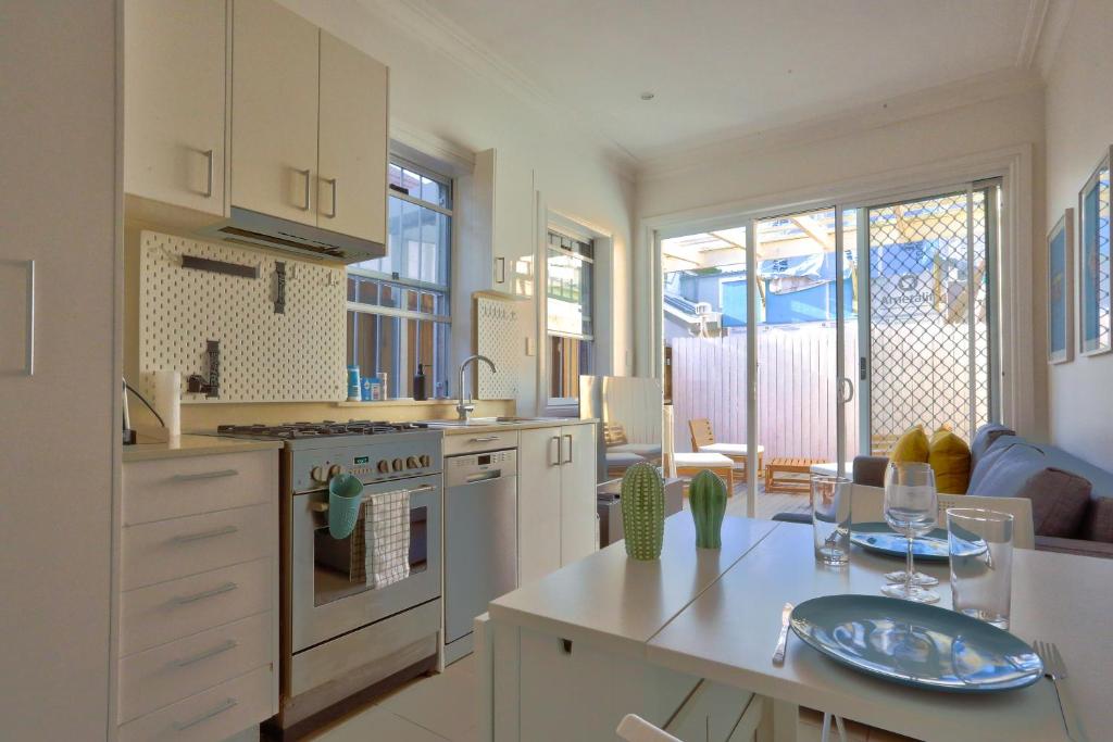 a kitchen with white cabinets and a table with wine glasses at 2 Bedroom House Situated at the Centre of Surry Hills 2 E-Bikes Included in Sydney