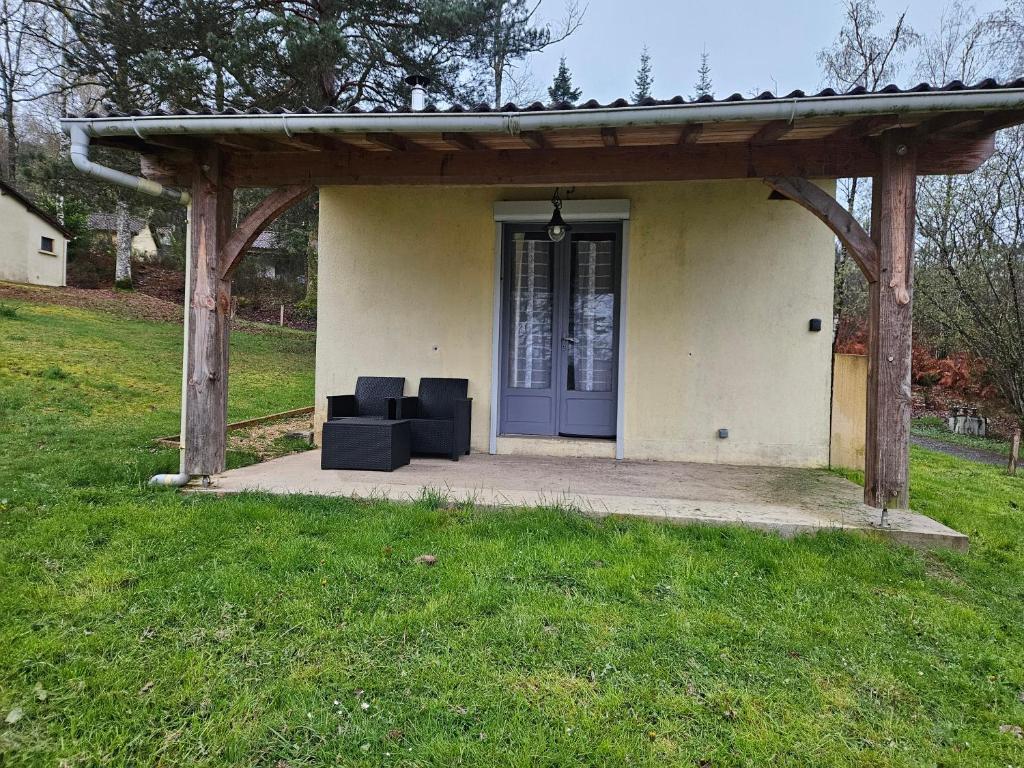 a porch with a blue door and two black chairs at Maison calme proche étang in La Coquille
