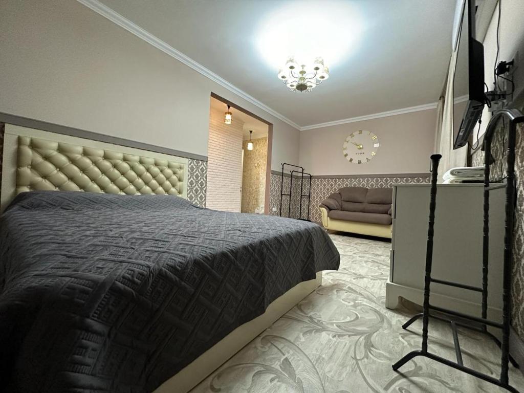een slaapkamer met een groot bed en een bank bij Апартаменты люкс класса in Karagandy
