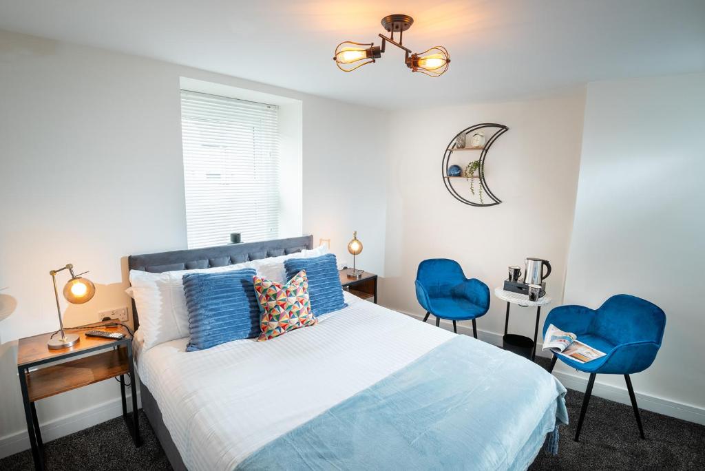 a bedroom with a bed and two blue chairs at Kings Arms Suites - Deluxe Room - En-Suite - Self Check In in Whitehaven