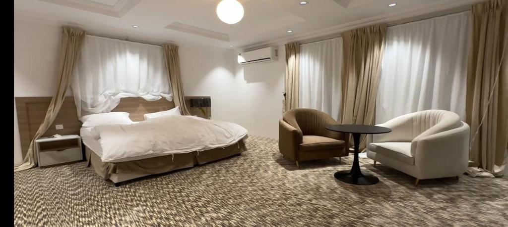 1 Schlafzimmer mit einem Bett, 2 Stühlen und einem Tisch in der Unterkunft Seven Star Hotel & Catering Service in Al Bad‘