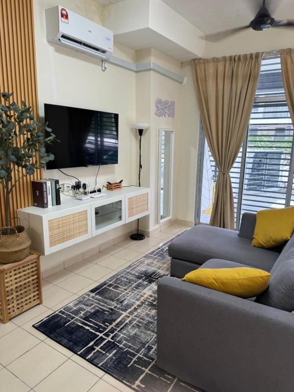 uma sala de estar com um sofá e uma televisão de ecrã plano em Orked Homestay em Bagan Serai