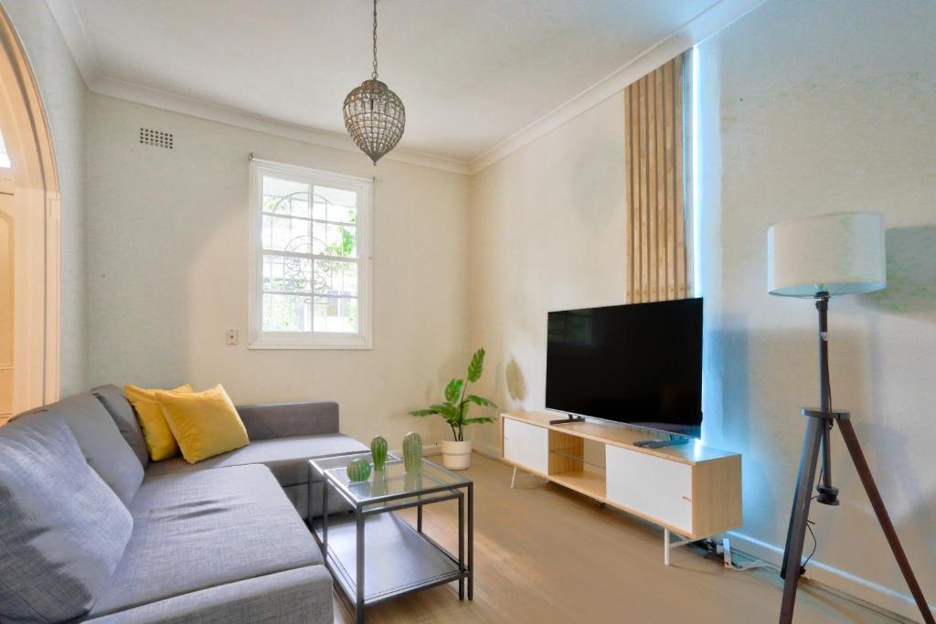 a living room with a couch and a flat screen tv at Ideal 3 Bedroom House in Chippendale with 2 E-Bikes Included in Sydney