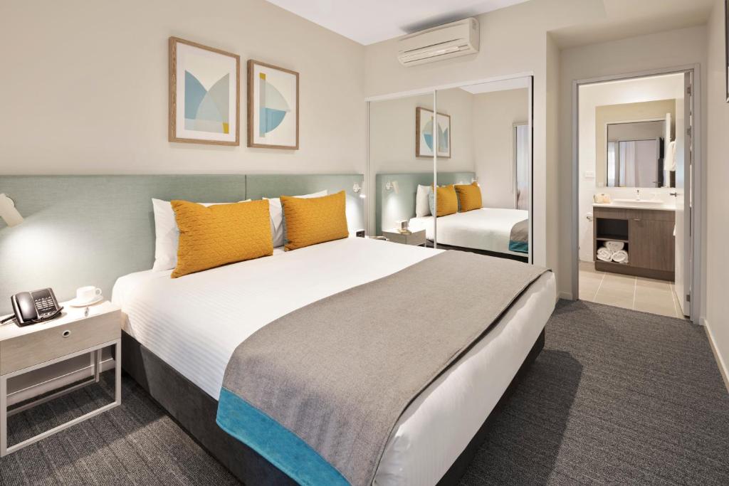 a bedroom with a large bed with orange pillows at Quest Eight Mile Plains in Brisbane