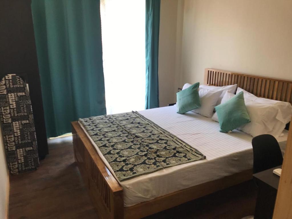 Schlafzimmer mit einem Bett mit grünen und weißen Kissen in der Unterkunft Chan Beach Resort & Hotel in Bahūr