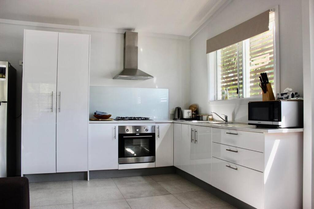 a kitchen with white cabinets and a stove top oven at CC's @ Byron Self Contained Studio in Byron Bay