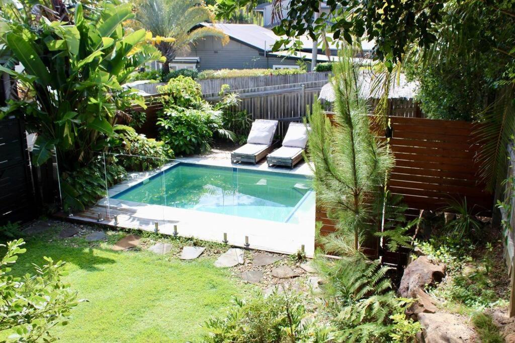 a small swimming pool in a garden with two loungers at CC's @ Byron Self Contained Studio in Byron Bay