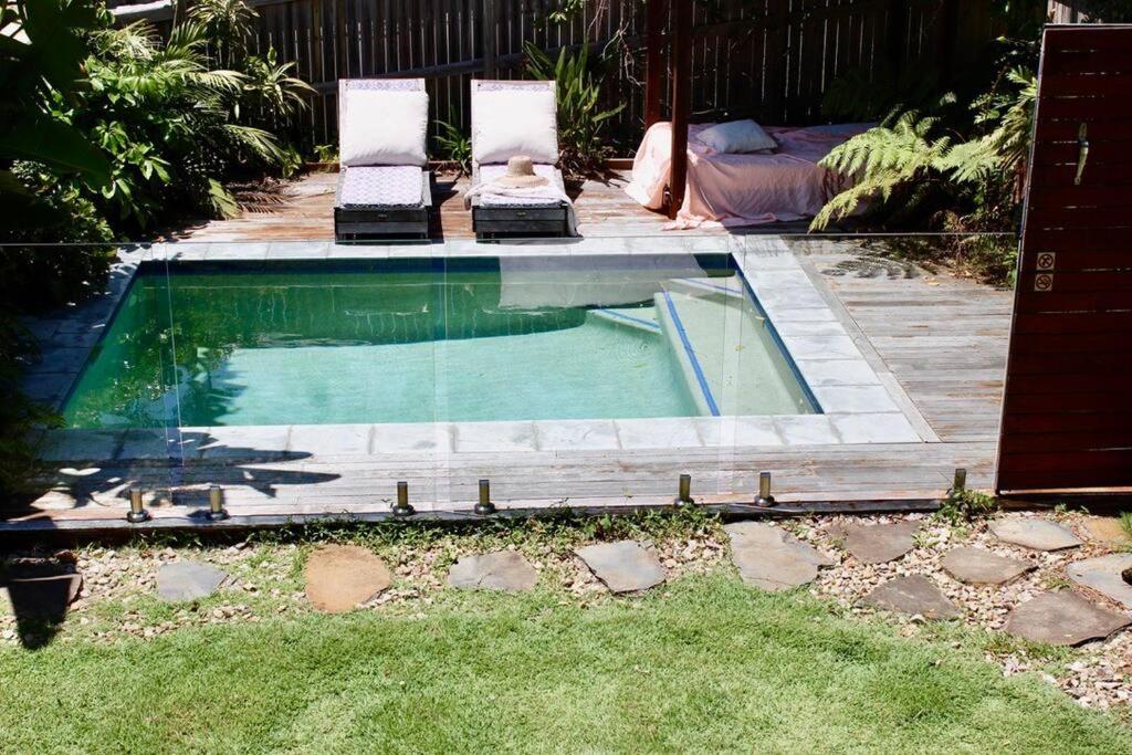 a swimming pool with two lounge chairs in a backyard at CC's @ Byron Self Contained Studio in Byron Bay