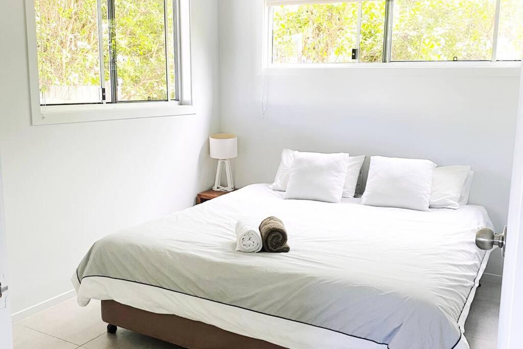 a white bed with a pair of shoes sitting on it at CC's @ Byron Self Contained Studio in Byron Bay