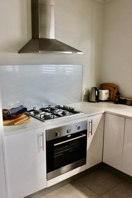 a white kitchen with a stove top oven at CC's @ Byron Self Contained Studio in Byron Bay