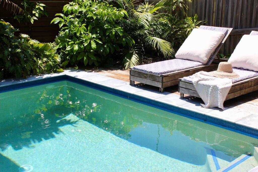 a swimming pool with a chair and a couch next to it at CC's @ Byron Self Contained Studio in Byron Bay