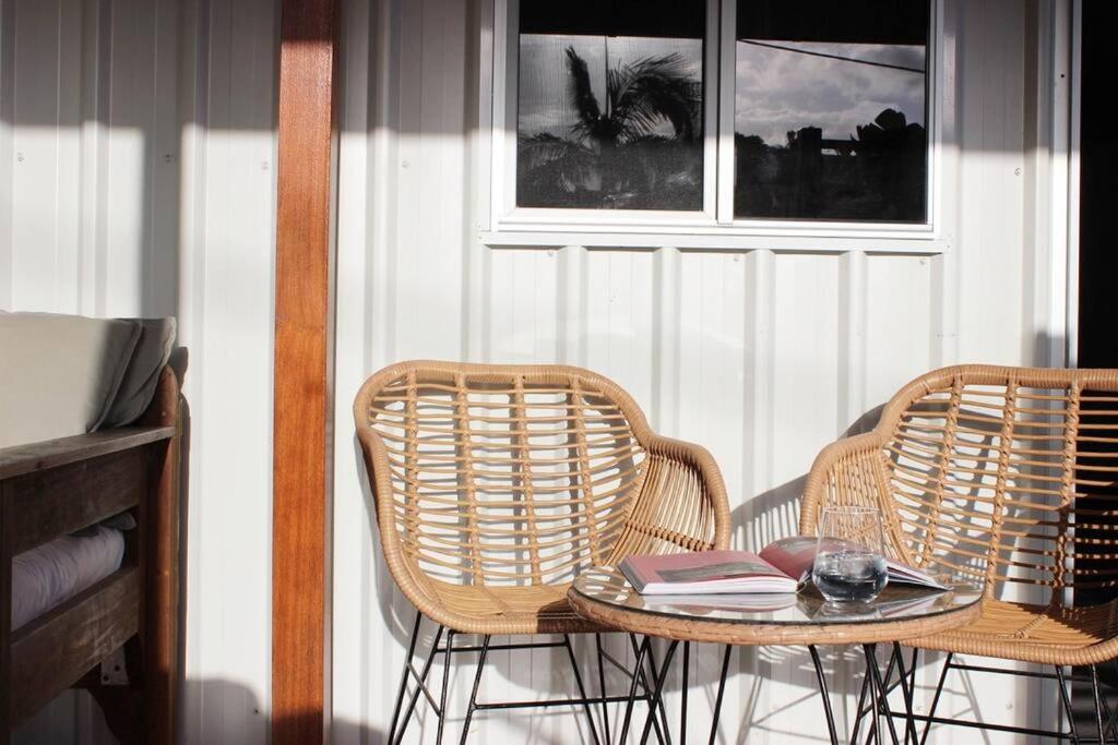 a rattan table with two chairs and a table with books at CC's @ Byron Self Contained Studio in Byron Bay