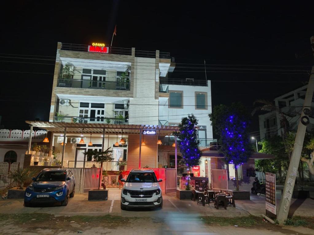 een wit gebouw met twee auto's ervoor geparkeerd bij Hotel Grand Mala in Jaipur