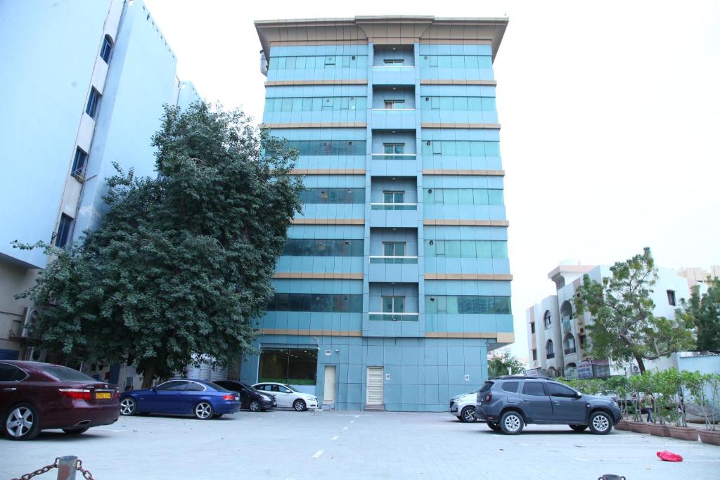 a tall building with cars parked in a parking lot at Zenith Smart Vacation Homes, Ajman in Ajman 