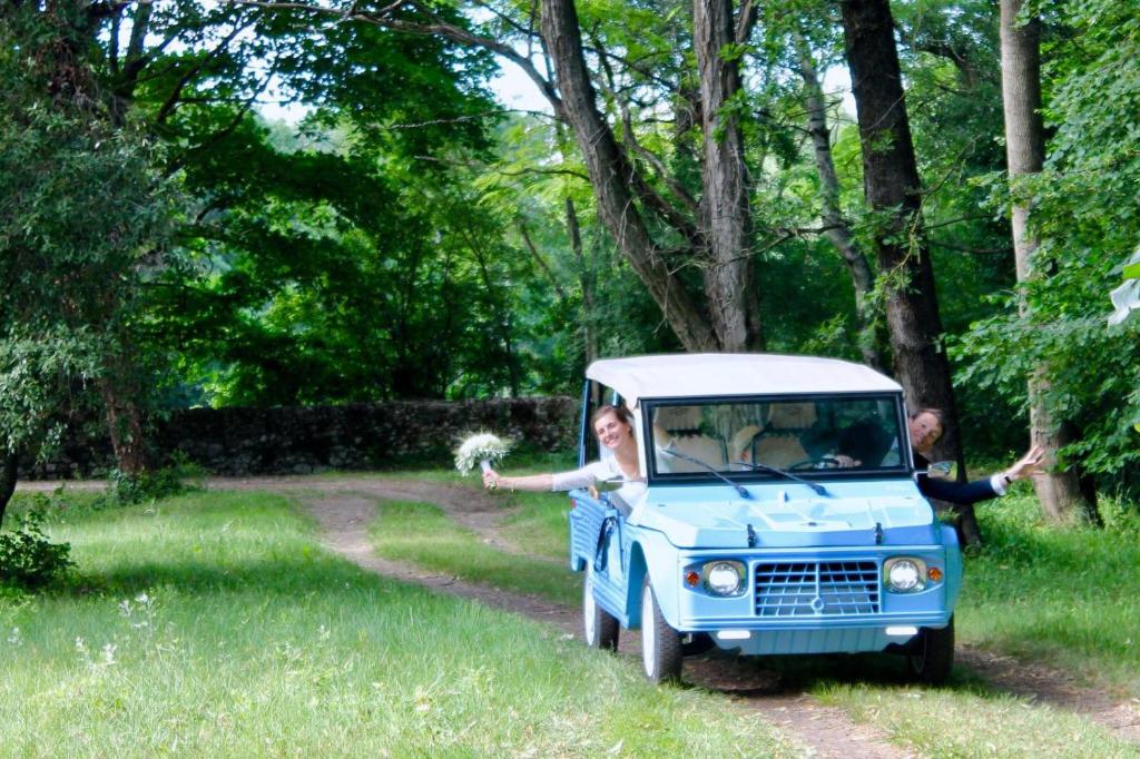 une femme conduisant un petit camion bleu et blanc dans l'établissement Chambres d'hôtes - Le Mas du Colombeyras, à Espeluche