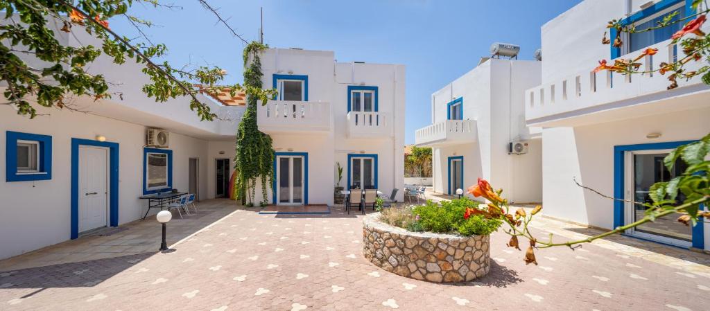 a courtyard with white buildings with blue doors at Alexis Apartments in Stavros