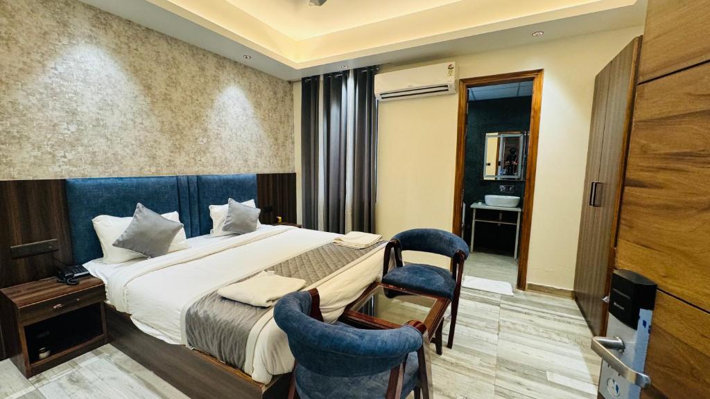 a hotel room with a bed and two chairs at Raksha Suites & Banquet Greater Noida in Greater Noida
