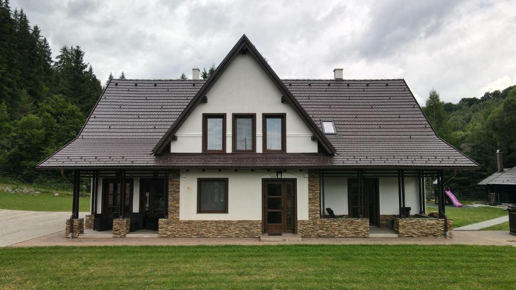 a white house with a black roof at Mountain Paradise & Wellness in Izvoare