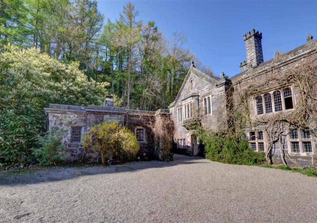 an old stone house with a driveway in front of it at The Gatehouse in Llanrwst