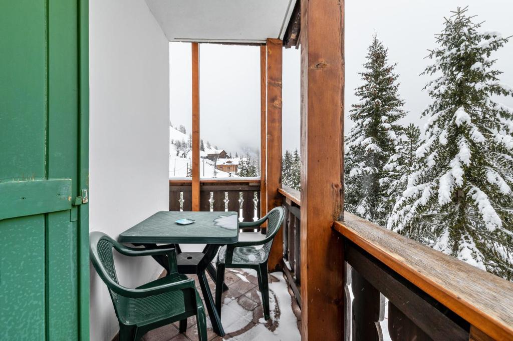 a table and chairs on a balcony with a snow covered tree at Appartamento Aurone in Arabba