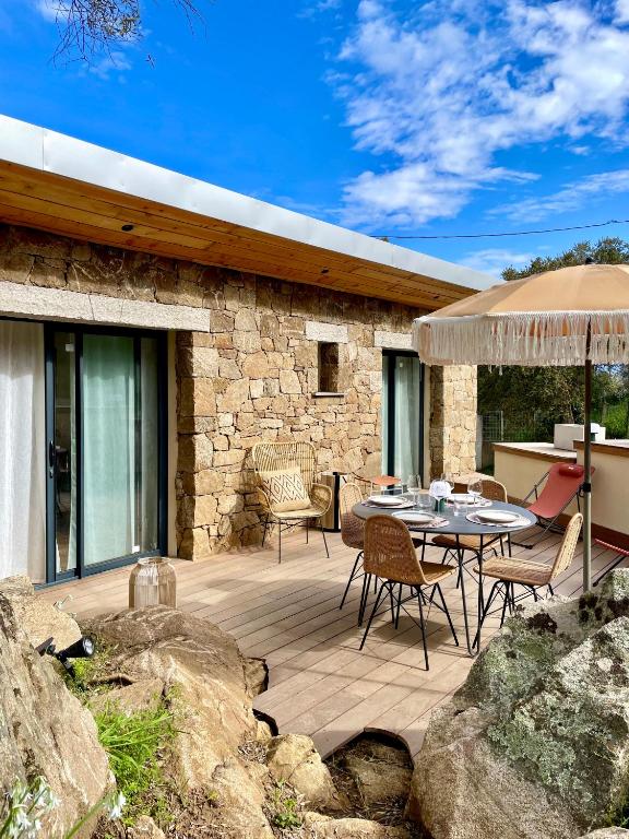 un patio avec une table, des chaises et un parasol dans l'établissement Caseddu 100m de la plage, à Belvédère