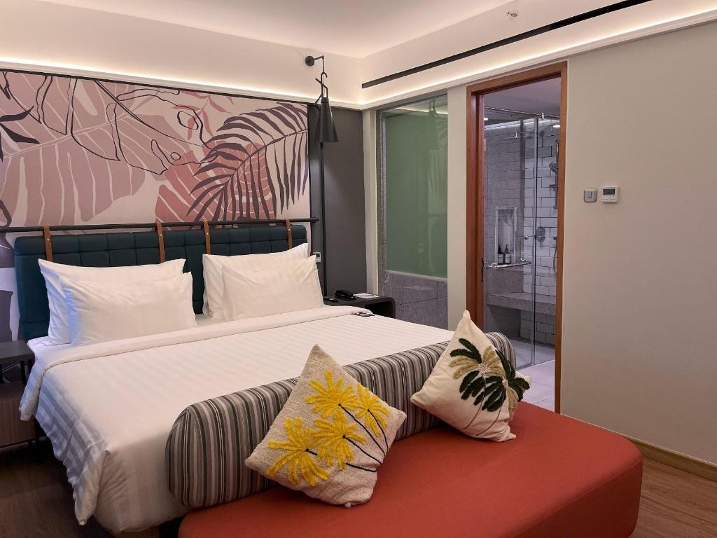 a bedroom with a large bed and a red bench at Luminor Hotel Legian Seminyak - Bali in Seminyak