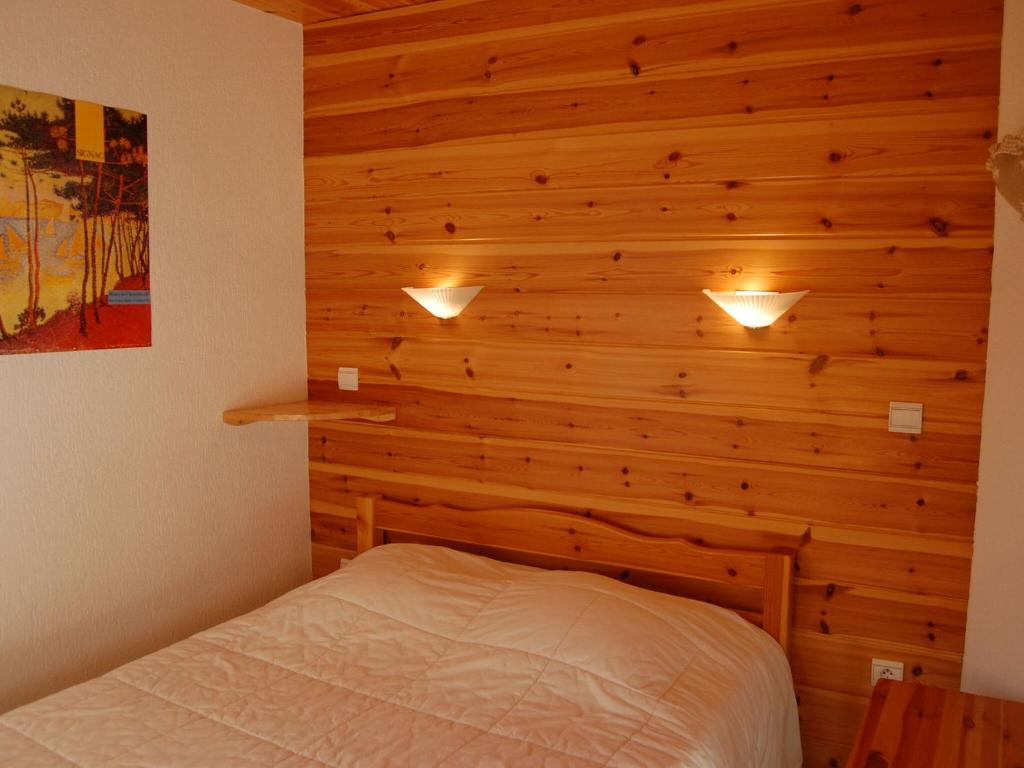a bedroom with a wooden wall with a bed at Spacious holiday home near center of Champagny in Le Villard