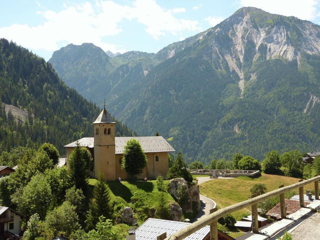 a church on a hill with mountains in the background at Spacious holiday home near center of Champagny in Le Villard