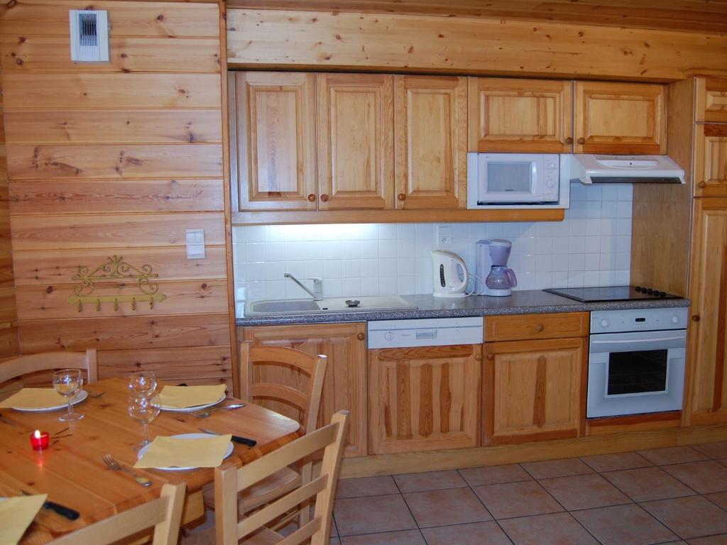 a kitchen with wooden cabinets and a table with chairs at Spacious holiday home near center of Champagny in Le Villard