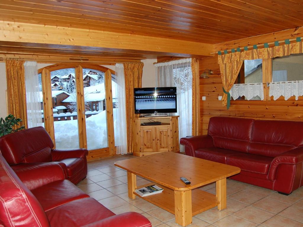 a living room with red leather furniture and a tv at Spacious holiday home near center of Champagny in Le Villard