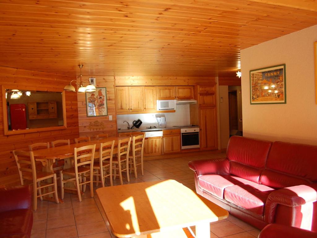 a living room with a red couch and a kitchen at Spacious holiday home near center of Champagny in Le Villard